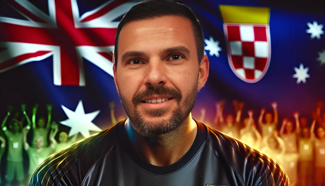 Ante Čović, een voormalig professioneel voetballer en doelman, met een kaal hoofd en een lichte huid, kijkt zelfverzekerd in de camera terwijl hij een keeperstenue draagt. Op de achtergrond zijn Australische en Kroatische vlaggen te zien, die zijn erfgoed vertegenwoordigen, evenals levendige kleuren die symbool staan voor zijn energieke persoonlijkheid.